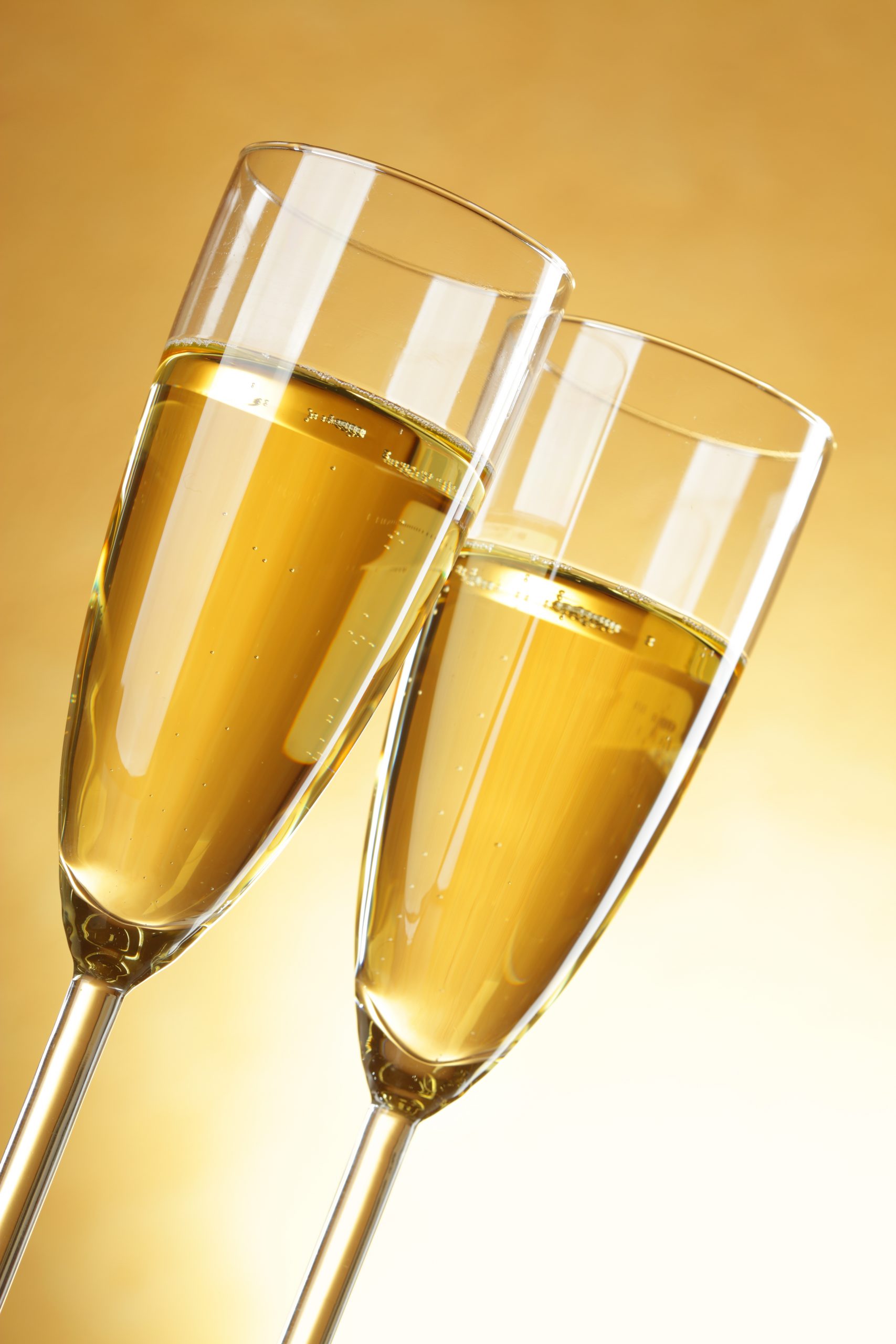 Two glasses of champagne over yellow background